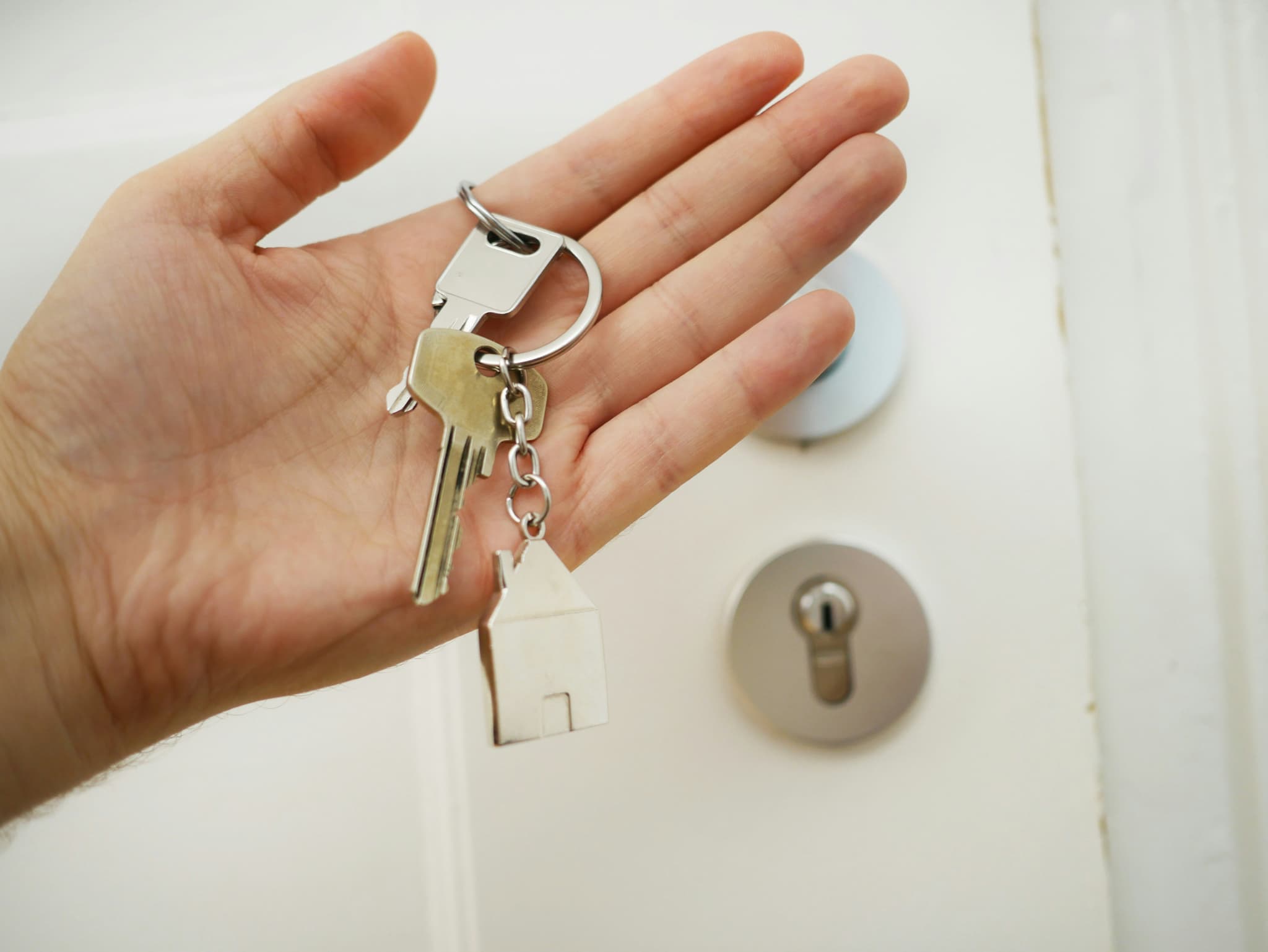 hand-holding-keys-with-a-houseshaped-keychain-near-a-door-lock